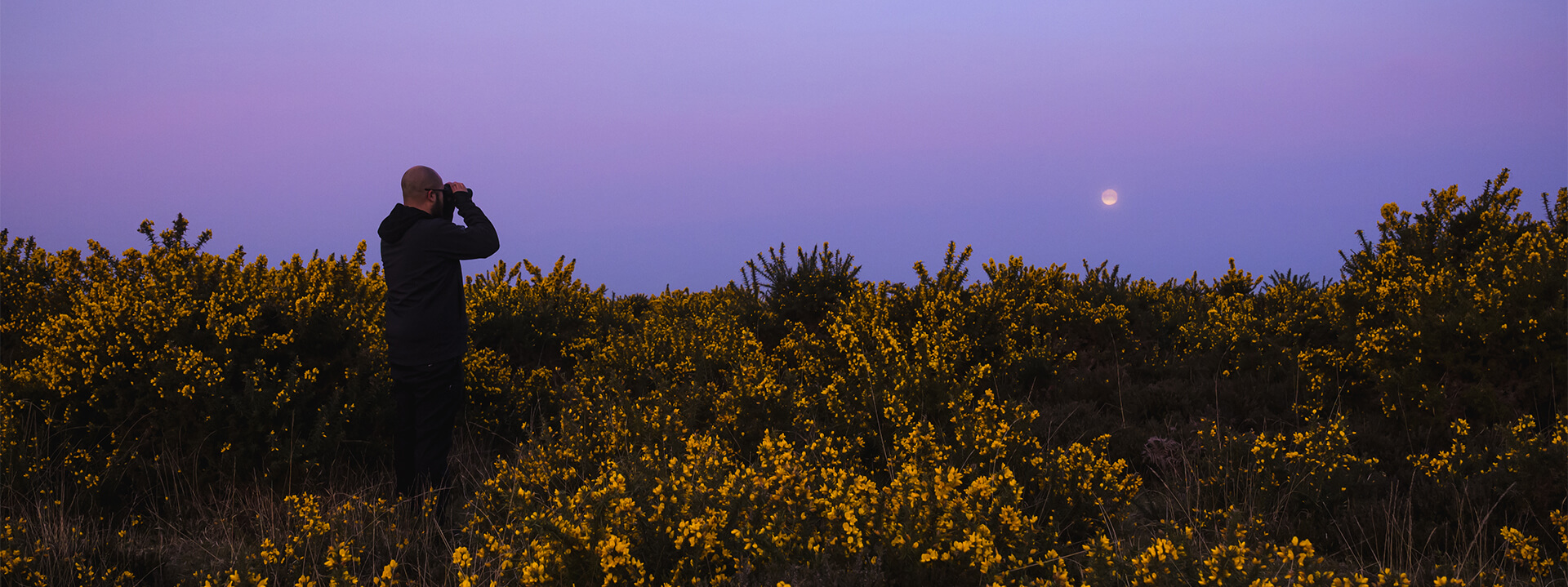 Muž sledující stmívající oblohu s dalekohledem Nikon PROSTAFF P7 10x42