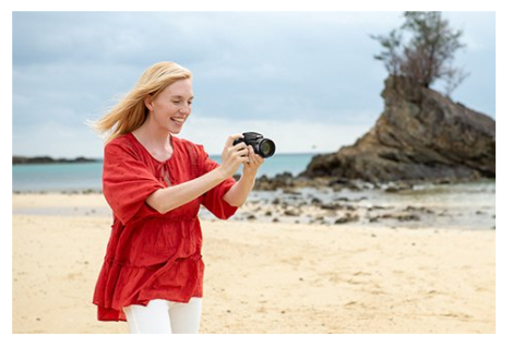Digitálny fotoaparát Nikon COOLPIX B600,žena na pláži s fotoaparátom v ruke