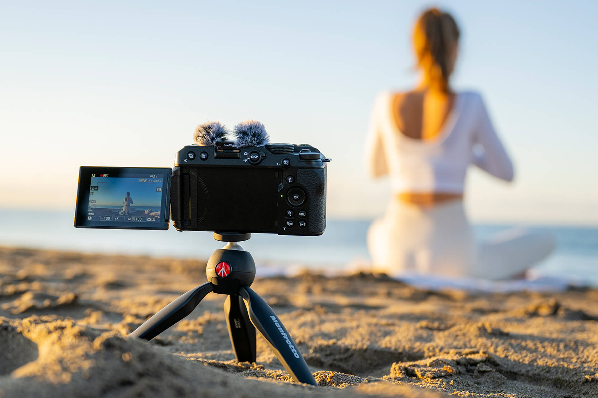 Digitálny fotoaparát Nikon Z30 na pláži pri slečne cvičiacej jogu