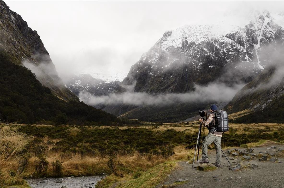 Fotograf s batohom Lowepro fotí zasnežené hory.