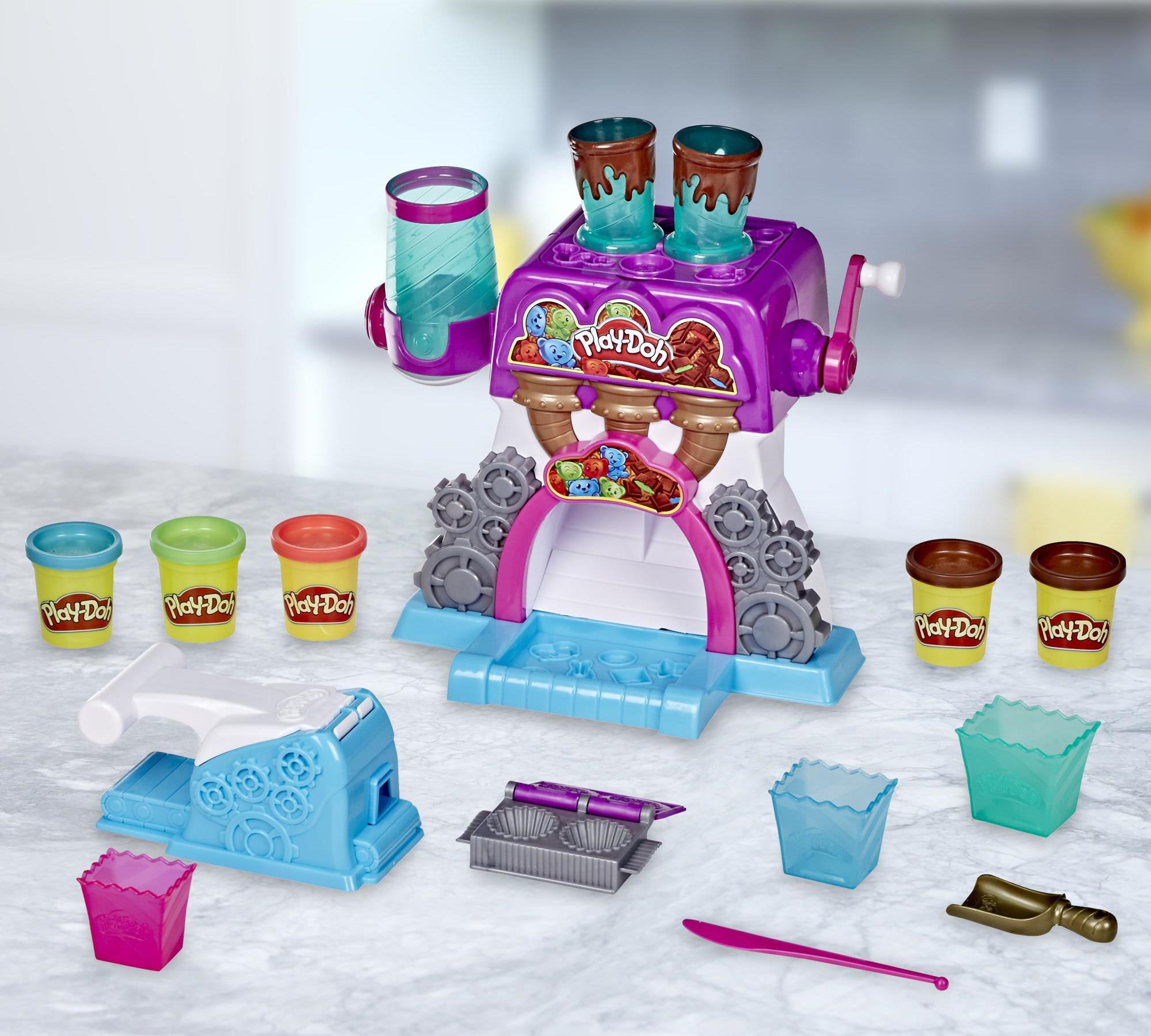 Herní sada Hasbro Play-Doh Továrna na čokoládu obsahuje cukrářský stroj, 5 kelímků, 3 poháry, lžíci, nůž, lis, formičku a modelínu, ze které děti mohou tvarovat cukrářské speciality dle své fantazie.