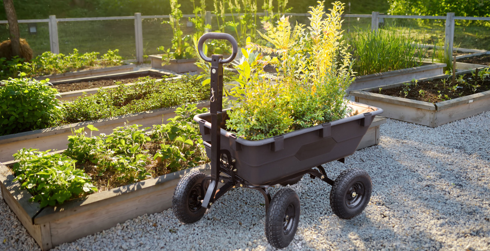 Zahradní vozík G21 mezi záhony s naloženou pytlovanou zeminou a květináči