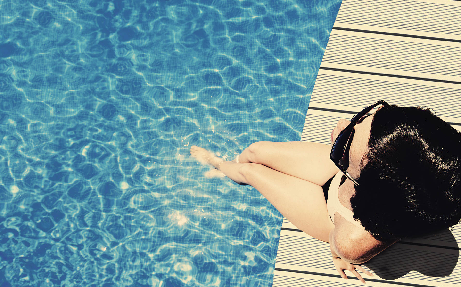 Egy nő a WPC terasz padlóburkolaton ülve medence mellett