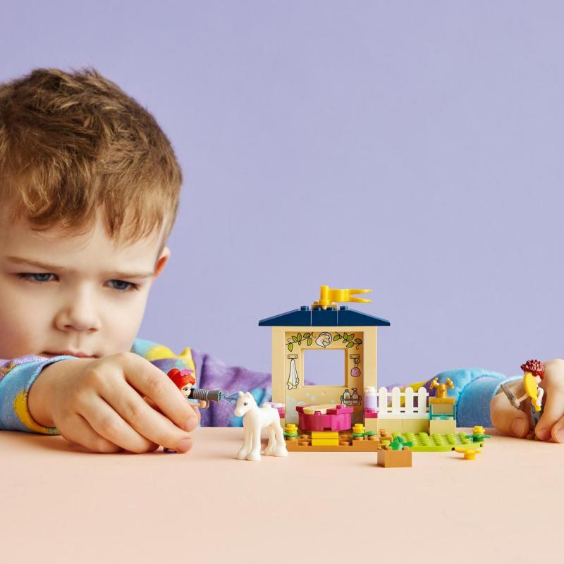 Chlapec si hraje se stavebnicí LEGO Čištění poníka ve stáji