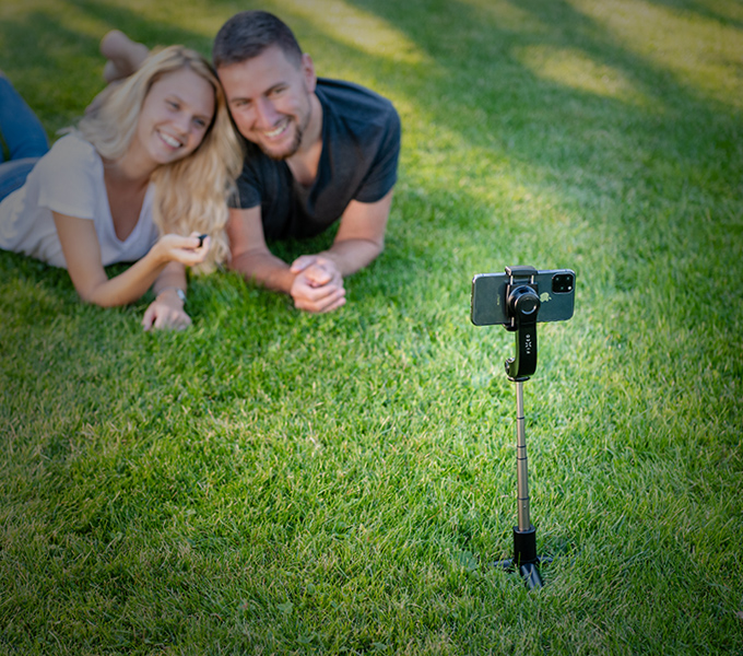 Pár fotiaci sa v ľahu na tráve s selfie Tripod FIXED Snap Action