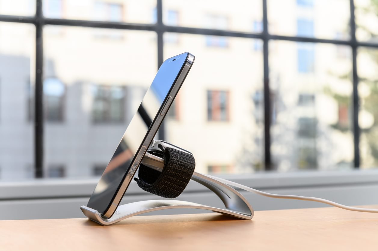 Mobilný telefón na stojane s hodinkami Apple Watch v nabíjačke