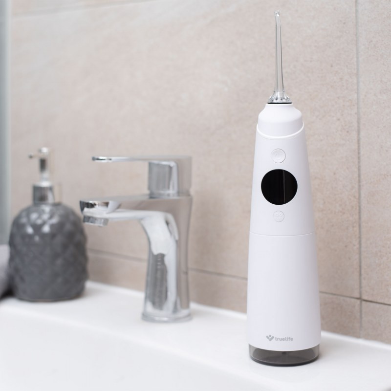 Ústní sprcha TrueLife AquaFloss Compact C300 umístěná na stolku v koupelně